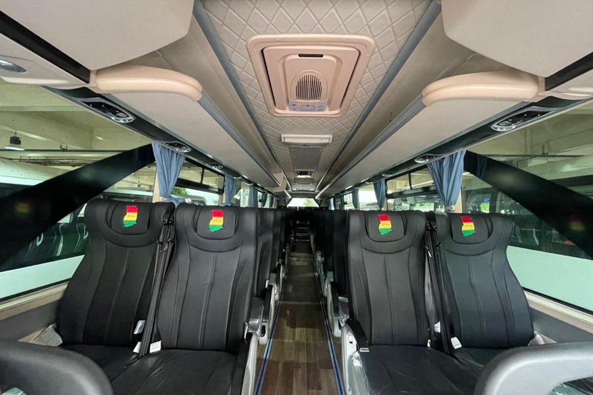 Inside a B.T.L.L. bus with cushioned seats and Ghana flag headrest covers
