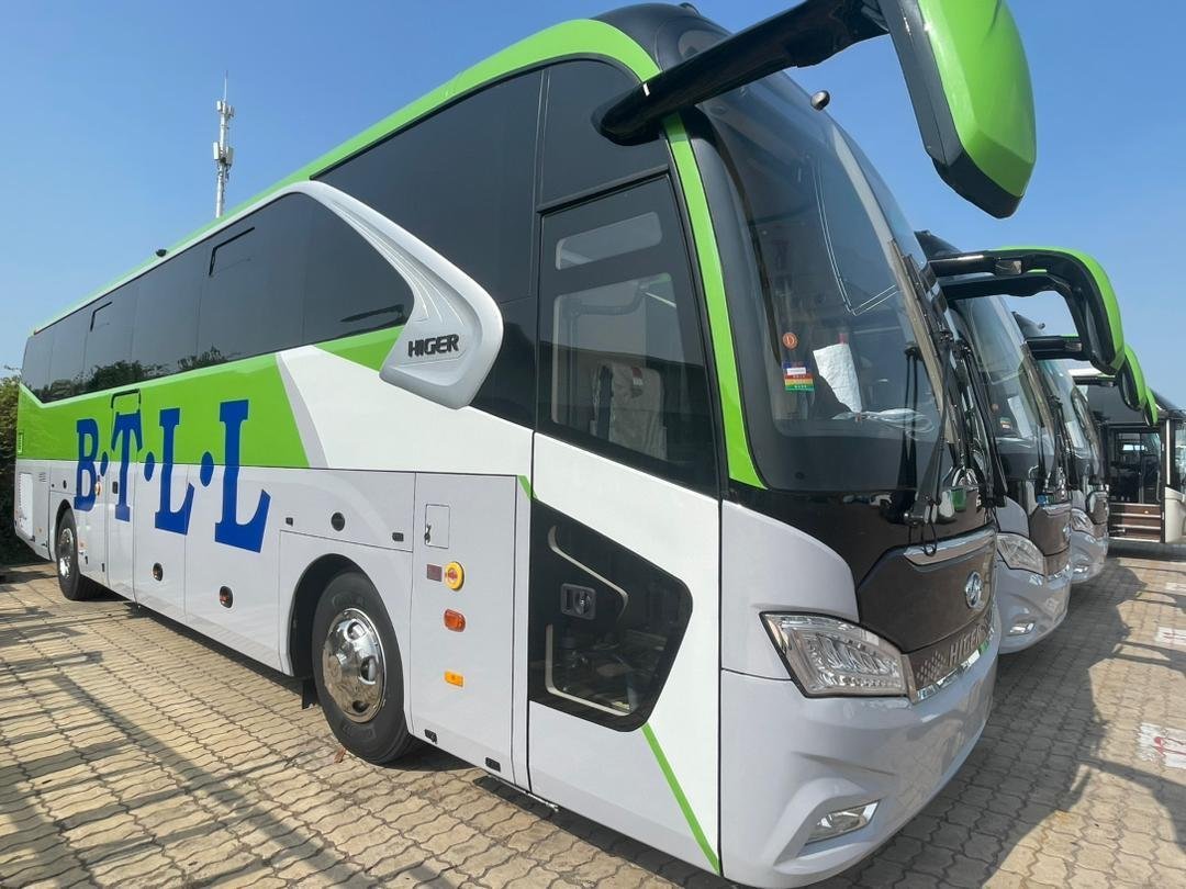 A white and green B.T.L.L. Higer bus parked in the sunshine